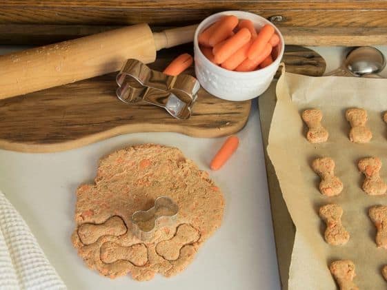Bone shaped dog treats, baking tools and ingredients for homemade dog treats.