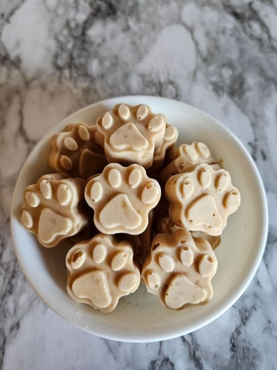 Paw shaped ice cream for dogs in a white bowl.