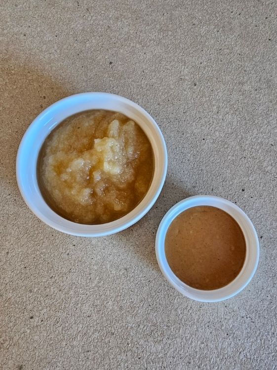 Applesauce and peanut butter in individual white bowls.