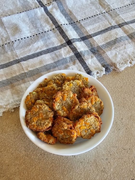 Cheesy zucchini bites in a white bowl next to a linen towel.
