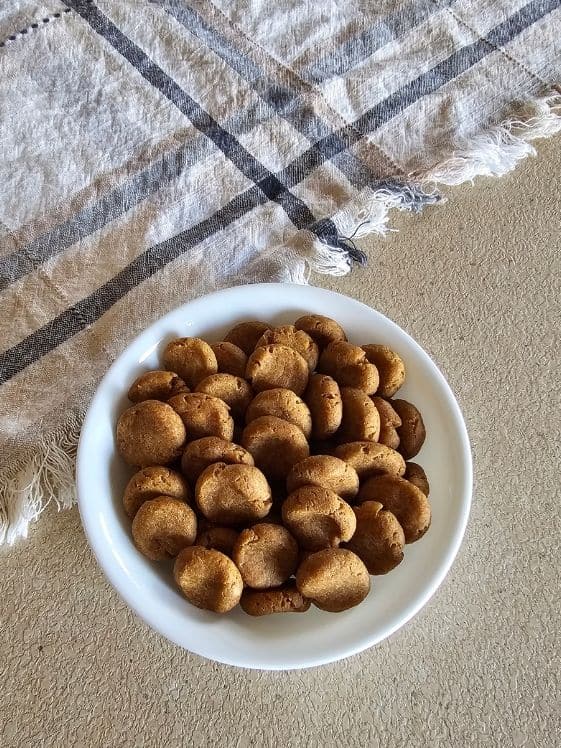 A white bowl of soft peanut butter sweet potato dog treats next to a linen towel.