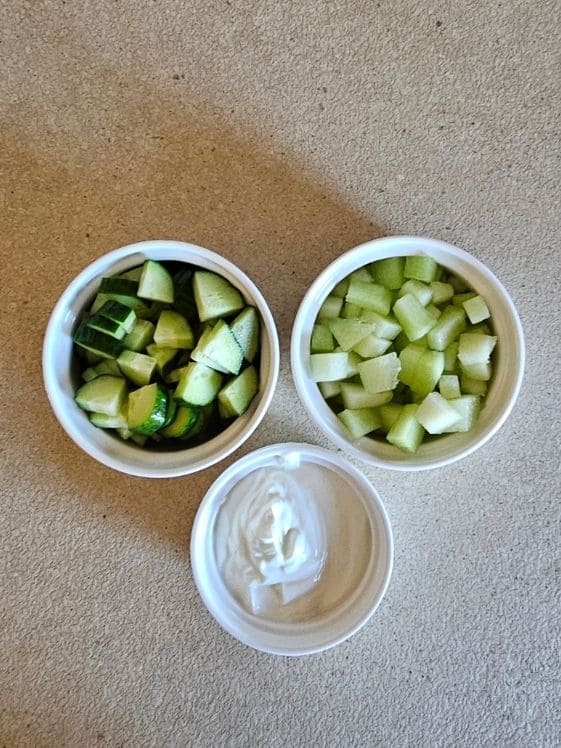Chopped cucumber, chopped honeydew melon, and plain Greek yogurt in individual white bowls.